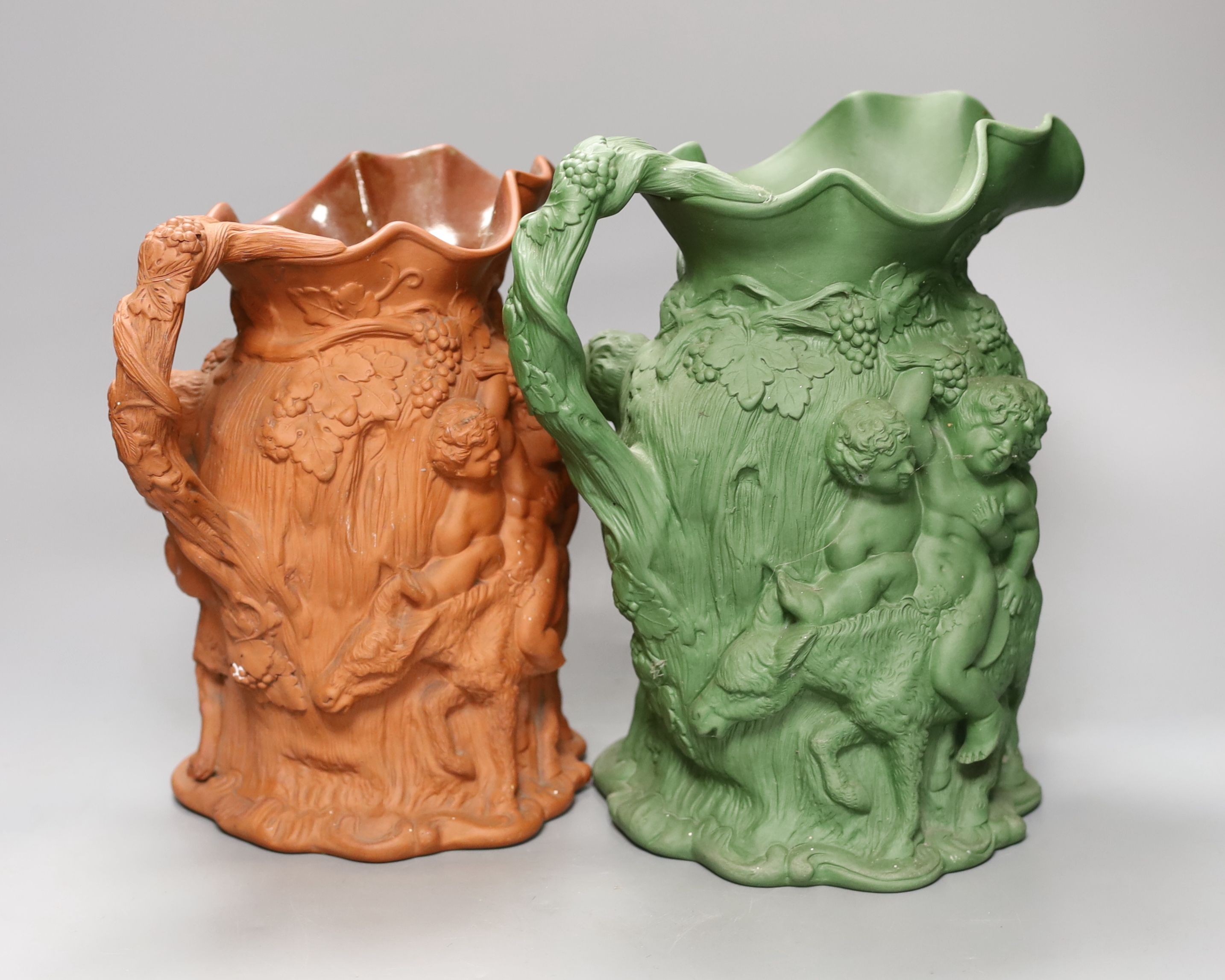 Two early 19th century terracotta Bacchanalian jugs, one green glazed 28cm